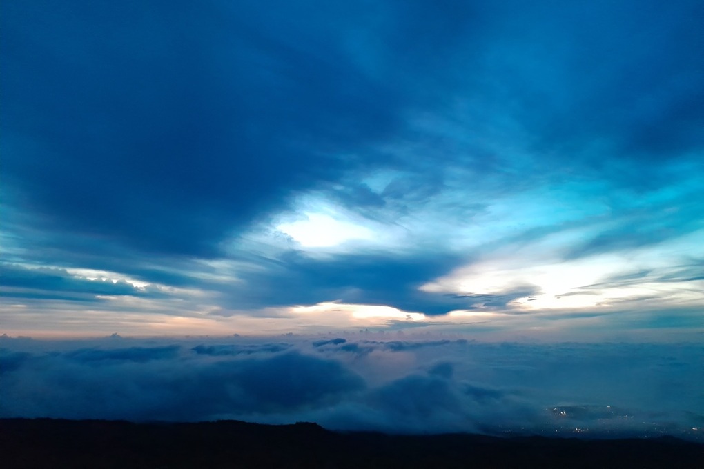 sunset above the clouds in La Réunion, with an intense blue sky and mystical light at Piton Maïdo