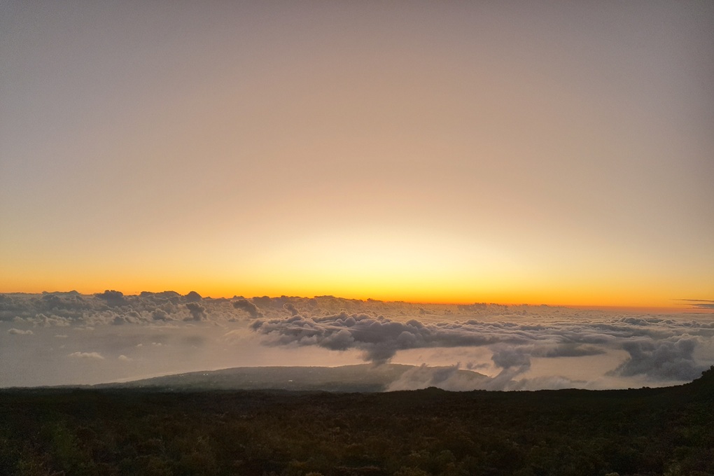 sunset in La Réunion, with a golden horizon and low clouds overlooking a volcanic landscape