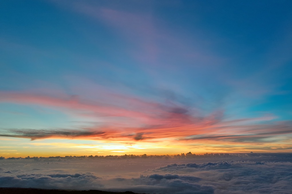 colourful sunset in La Réunion, with a blue and pink sky and thin clouds above a sea of clouds