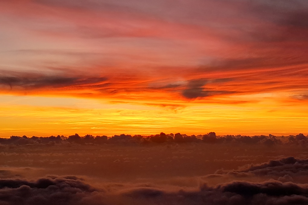 intense sunset in La Réunion, with a red-orange sky and a dark horizon above a sea of clouds