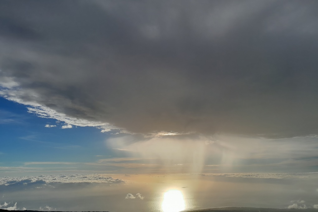 stormy sunset in La Réunion, with dark clouds and filtered light reflecting on the ocean