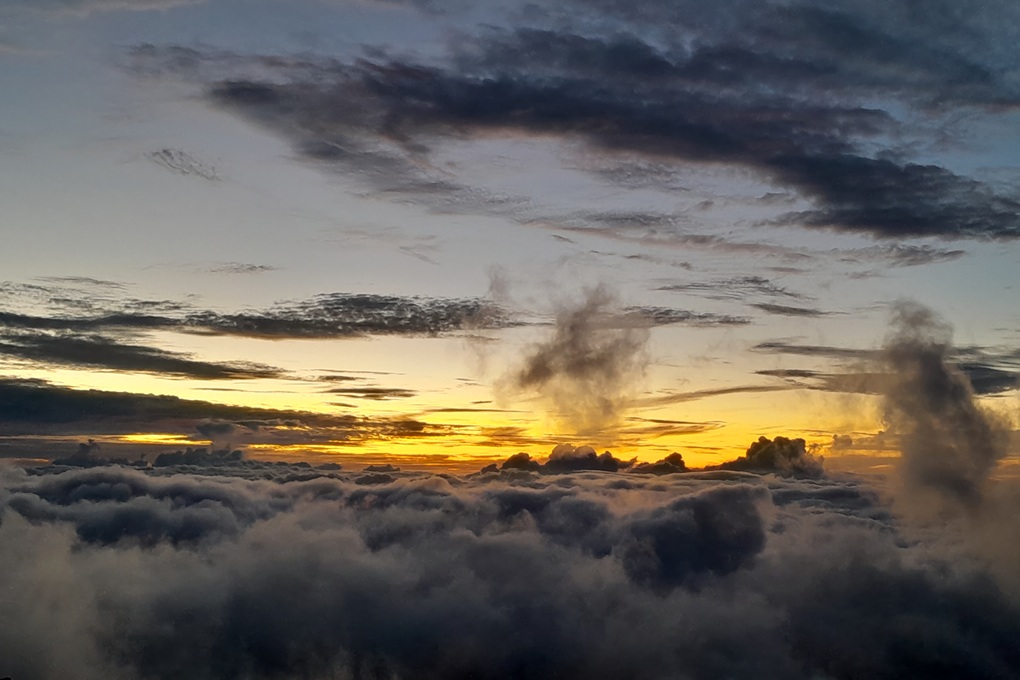 dramatic sunset in La Réunion, with dark clouds and golden light above a sea of clouds