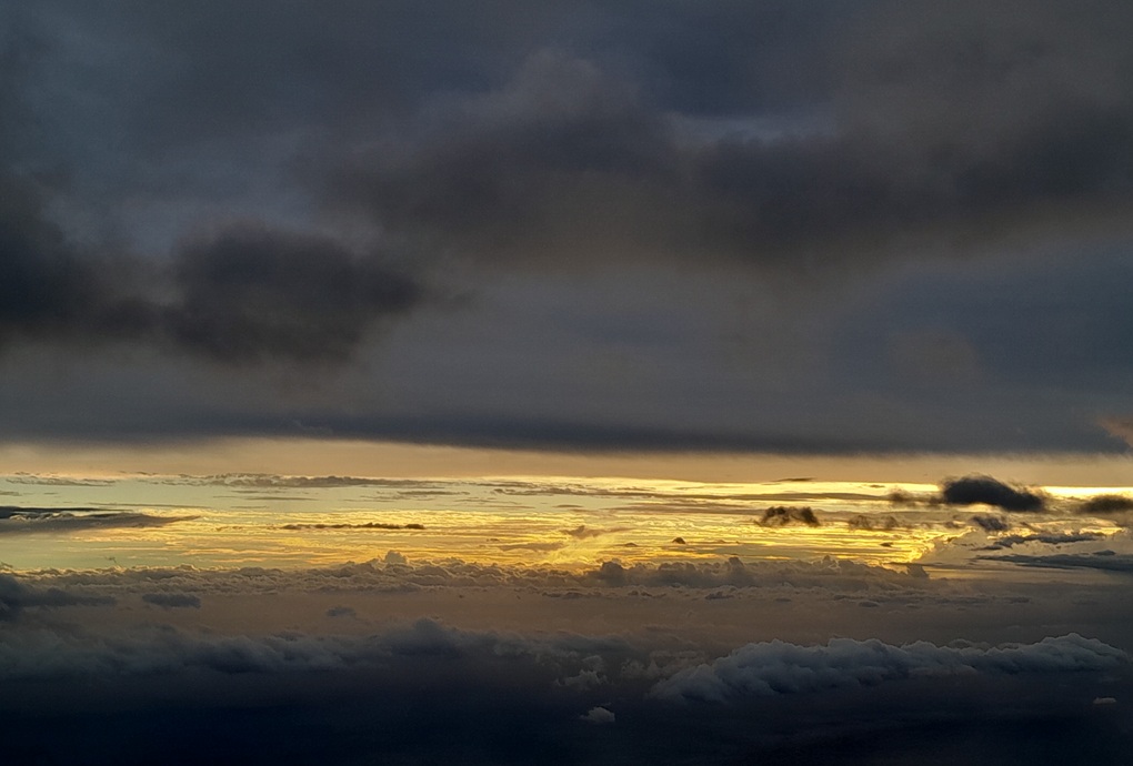 dark sunset in La Réunion, with thick clouds and golden filtered light at the horizon