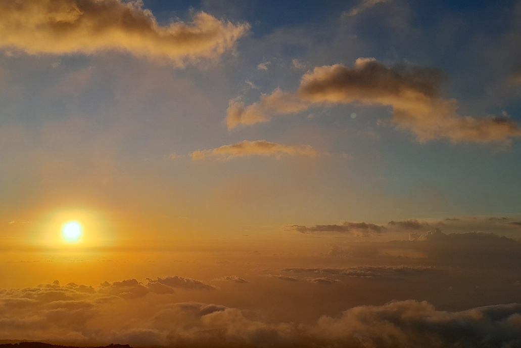 luminous sunset in La Réunion, with a low sun and a golden sky above a sea of clouds