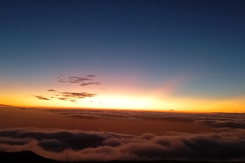 sunset in La Réunion, with a blue-to-orange gradient sky above a dark sea of clouds