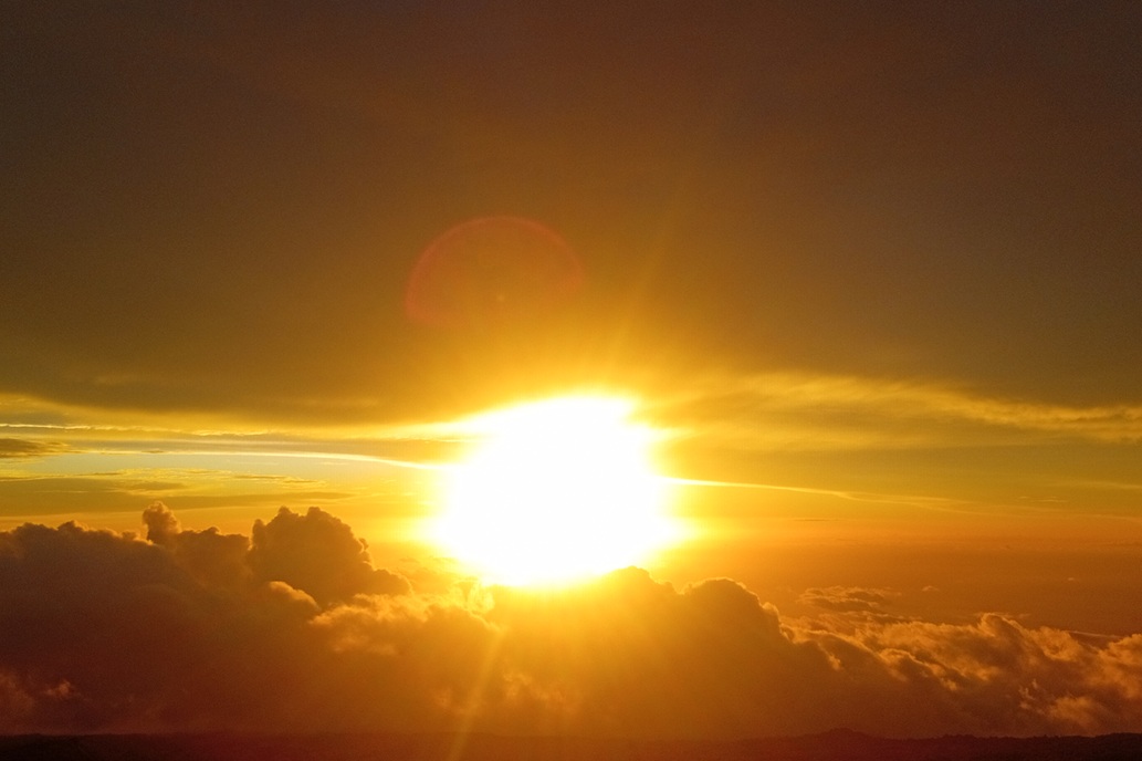 luminous sunset in La Réunion, with the setting sun over a sea of clouds and a deep orange sky