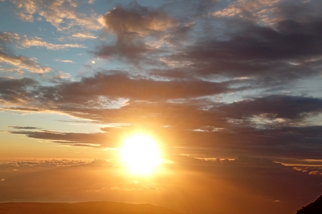 luminous sunset in La Réunion, with a radiant sun between the clouds and a partly covered sky