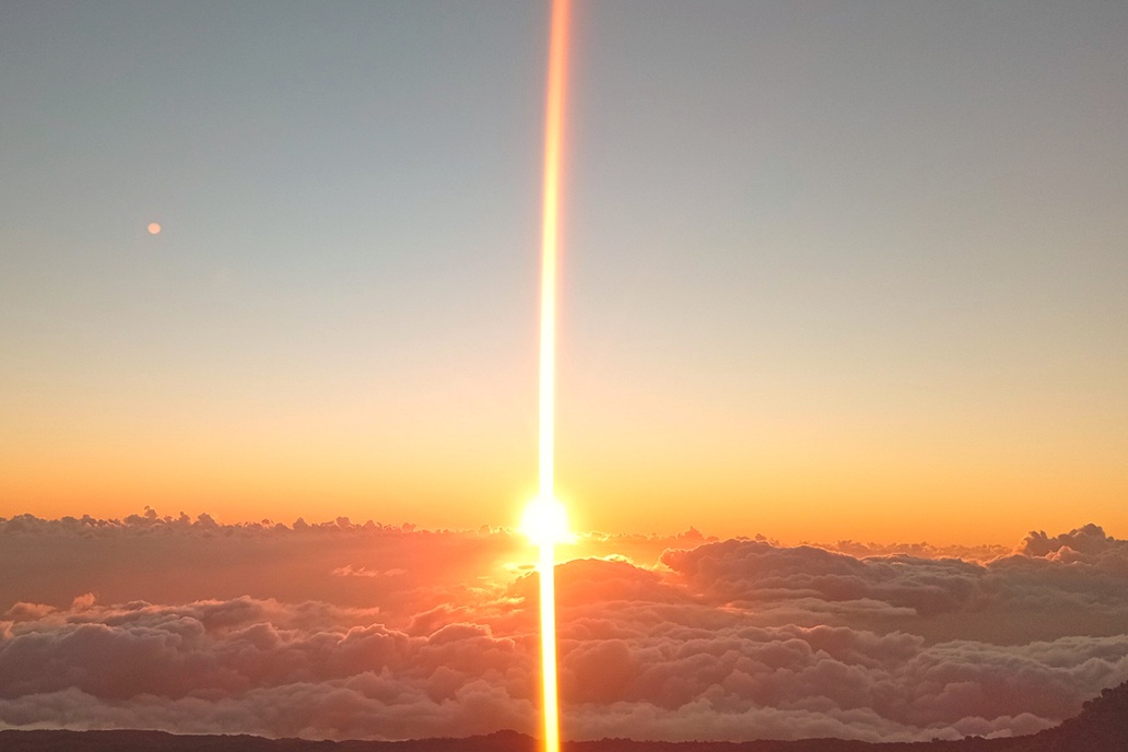 sunset in La Réunion, with the sun piercing the clouds and coloured mist above the ocean