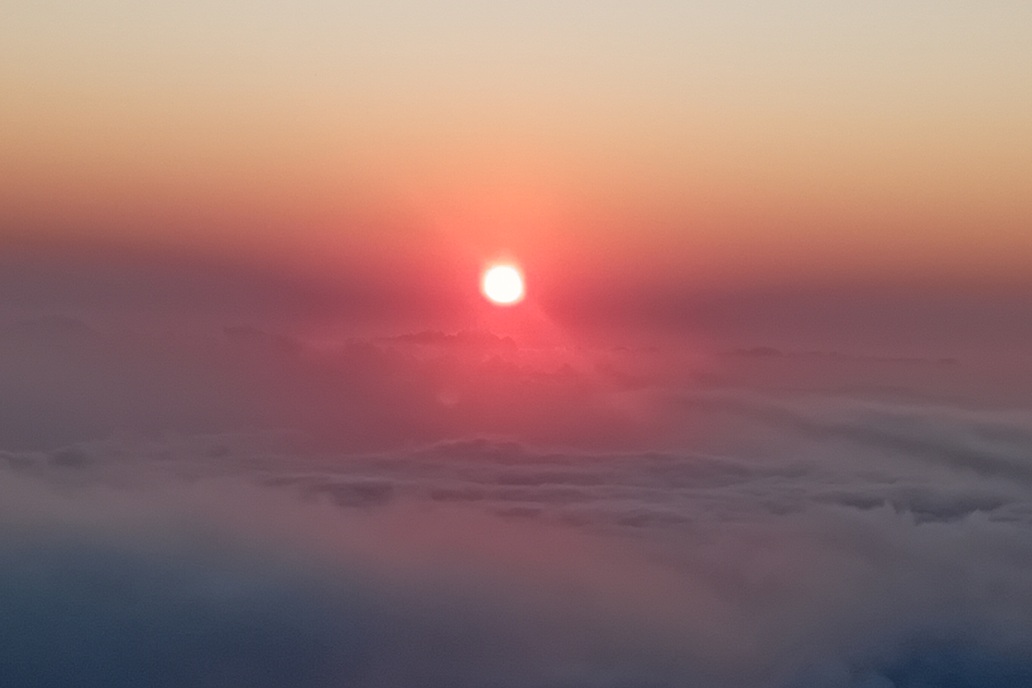 minimalist sunset in La Réunion, with the sun disappearing at the horizon above a calm sea of clouds