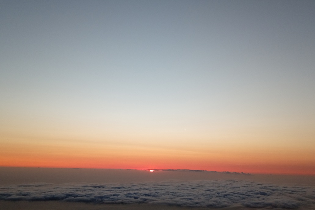 minimalist sunset in La Réunion, with the sun disappearing at the horizon above a calm sea of clouds