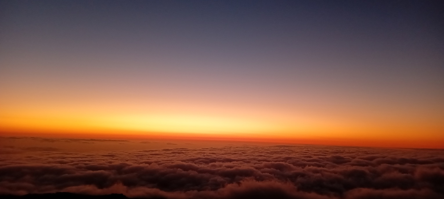 minimalist sunset in La Réunion, with an intense orange horizon and a uniform sea of clouds