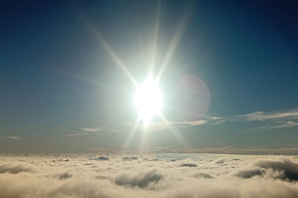 minimalist sunset in La Réunion, with the sun disappearing at the horizon above a calm sea of clouds