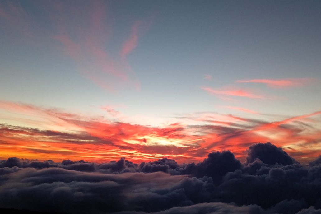 vibrant sunset in La Réunion, with an intense red sky and voluminous clouds above the ocean