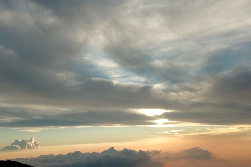 veiled sunset in La Réunion, with the sun hidden behind the clouds and soft light on the horizon