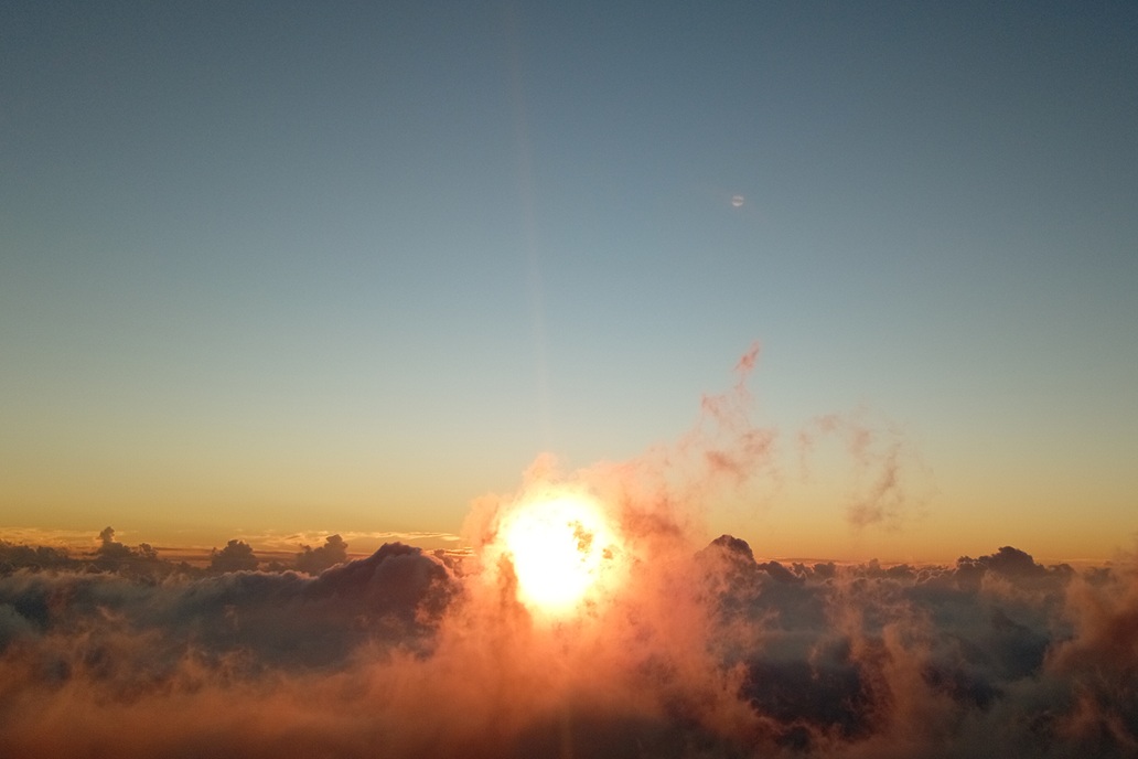 sunset in La Réunion, with the sun piercing through clouds and coloured mist above the ocean