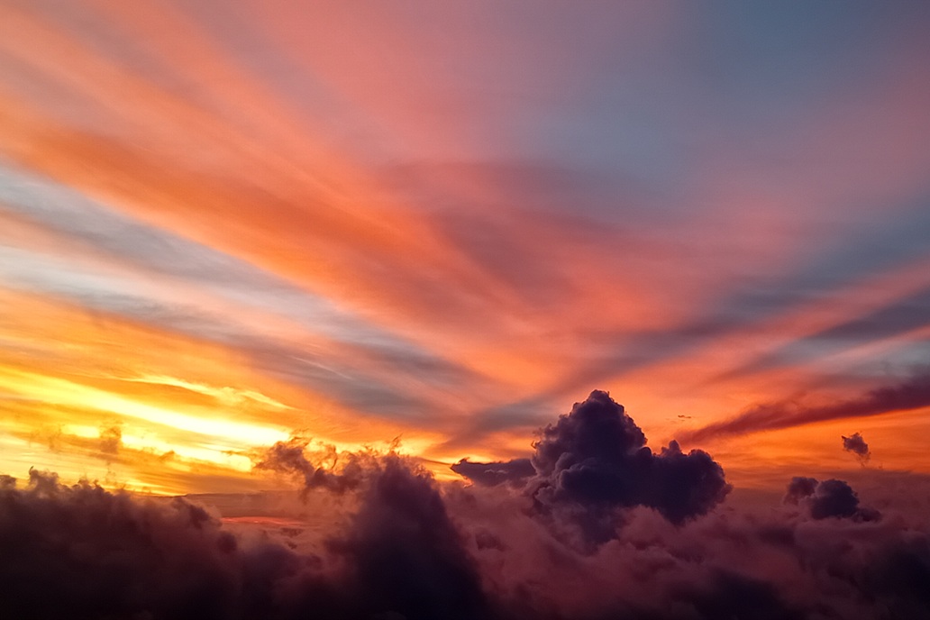 artistic sunset in La Réunion, with violet and orange clouds and a luminous sky above the clouds